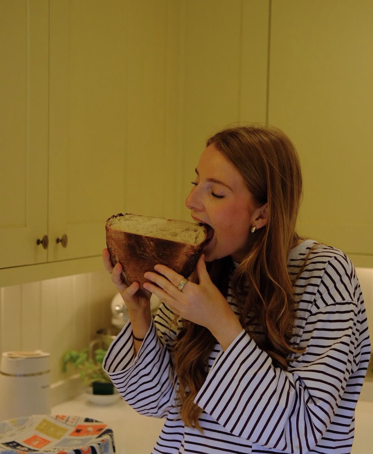Jess taking a bite straight out of a sourdough loaf